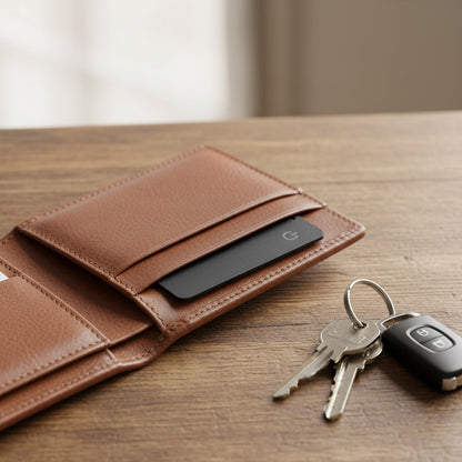 Traceur Bluetooth Zénithia ultra-mince noir inséré dans un portefeuille en cuir marron à côté d'un trousseau de clés.